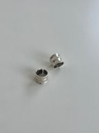 Two small silver-toned metal ring-like accessories with a split circular shape, photographed on a plain light gray surface.